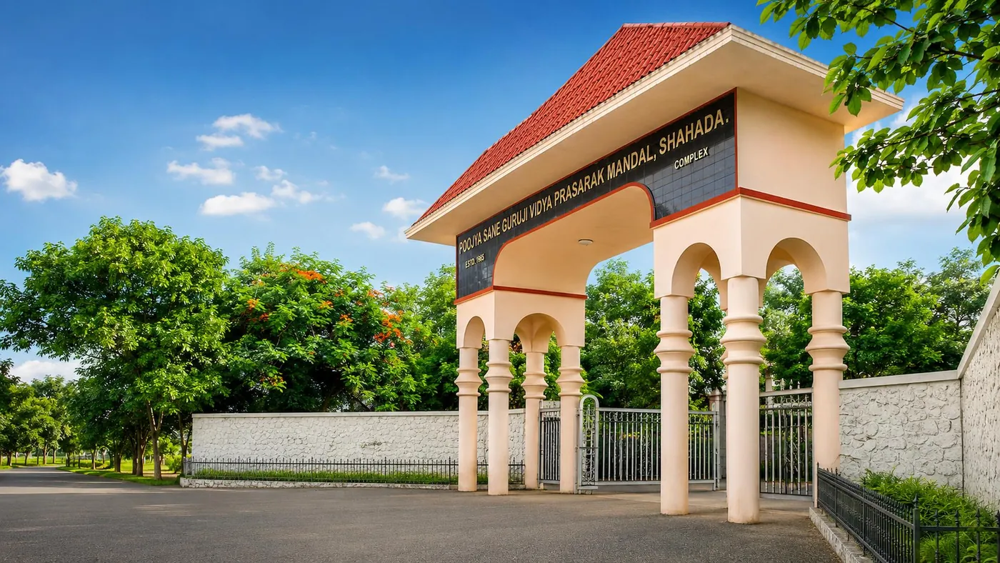The red-roofed entrance gate of the Mandal's campus at Shahada, with the Mandal's name on its arch, under a blue sky and green trees